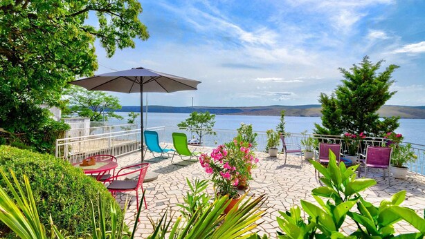 Une terrasse avec des sièges d’extérieur, une table et une plante en pot.