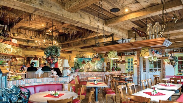 Un restaurante rústico con interiores de madera, paredes de ladrillo y diferentes opciones de asientos, como cabinas y mesas.