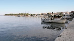 Un rivage paisible, avec des bateaux amarrés, une promenade dallée et des bâtiments en arrière-plan.