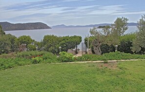 Uma área gramada com vista para um lago e montanhas ao longe.