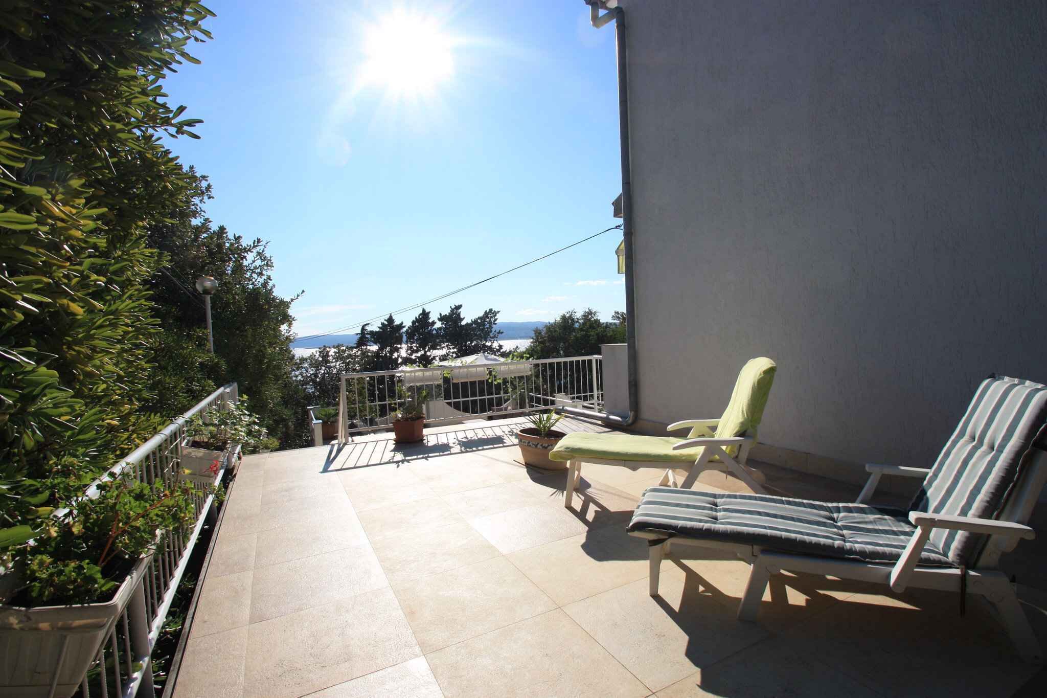 Un balcon avec deux fauteuils, une petite table et des plantes en pot.