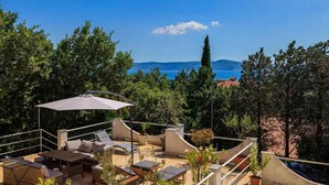 A rooftop terrace with outdoor furniture, a large umbrella, and a view of the sea. - Holiday apartment with terrace and sea view (Crikvenica)