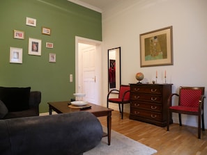 A living room with a green wall, a wooden dresser, a red chair, a globe, and a painting.