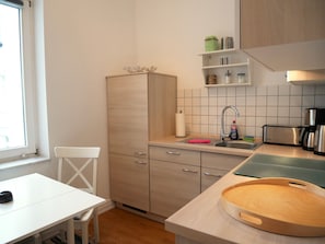 A compact kitchen with a sink, a toaster, and a wooden cutting board.