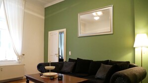 Un salon avec un canapé marron foncé, une table basse en bois et un mur vert.