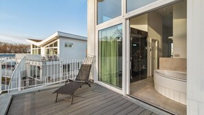 A modern building with a balcony, a glass door leading to a bathroom, and a small outdoor seating area. - Stunning apartment in Travemünde Waterfront with sauna (Travemünde Waterfront)