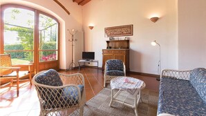Un saló confortable amb mobles de vimetla, una televisió i vistes a un jardí a través de grans finestres.