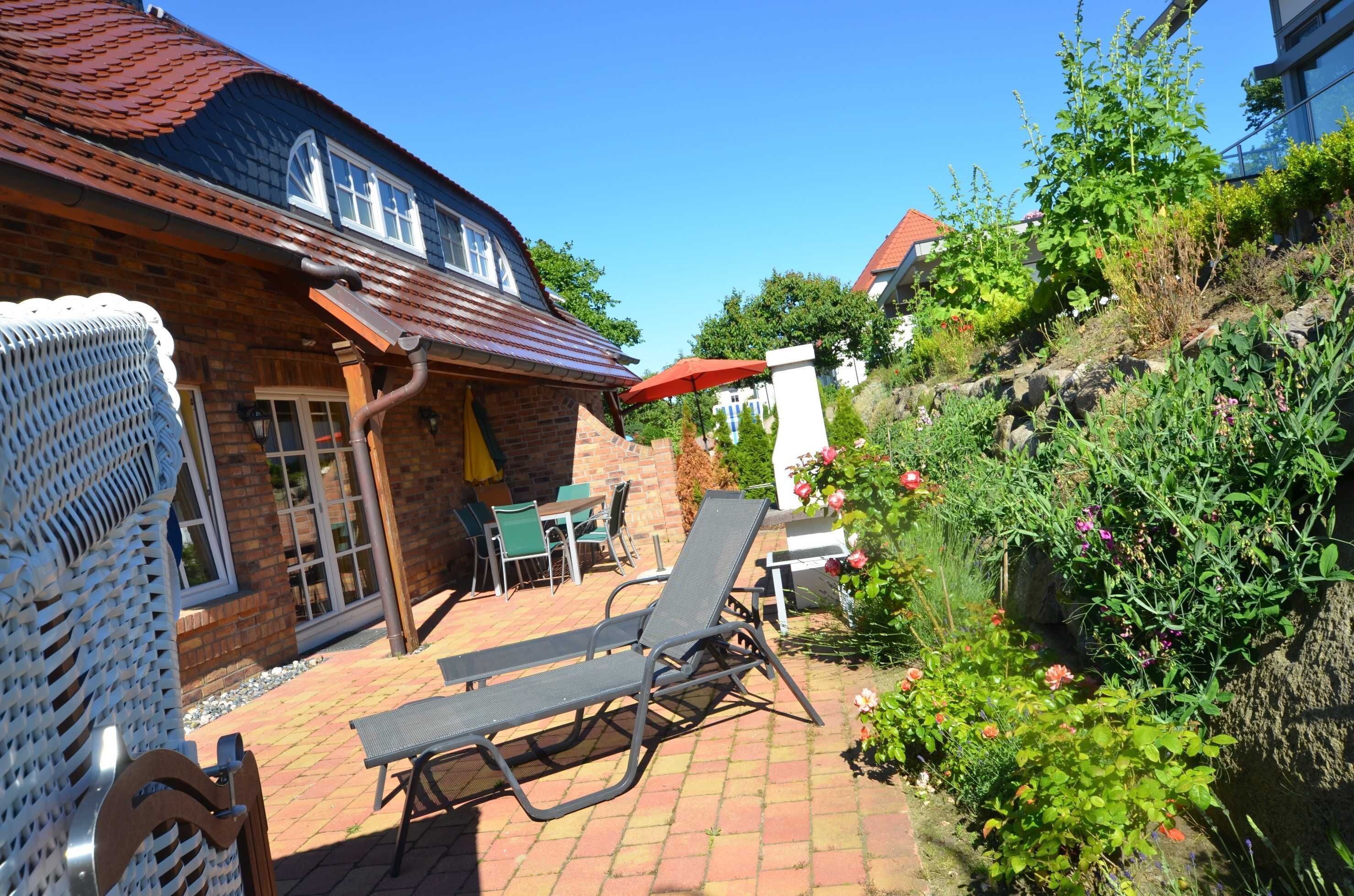 A patio area with a brick floor, outdoor furniture, and a red umbrella.