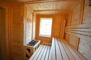 A wooden cabin interior with a bench, a window, and a small storage area. - 44a Haus Bel Air right half of the house - Landhaus Kröning TZR (Gager)