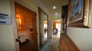 En hotellkorridor med trädörrar, en termostat, en inramad tavla och ett klinkergolv.