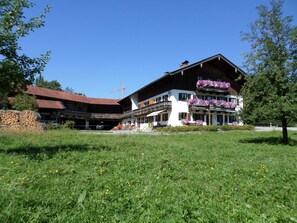 A traditional wooden building with balconies, a covered entrance, and a well-maintained lawn. - Double Room 2 - Haus Bamberger (Fischbachau)