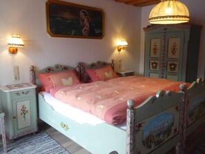 A bedroom with a bed, nightstands, a dresser, wall-mounted lights, and a painting. - Double Room 2 - Haus Bamberger (Fischbachau)