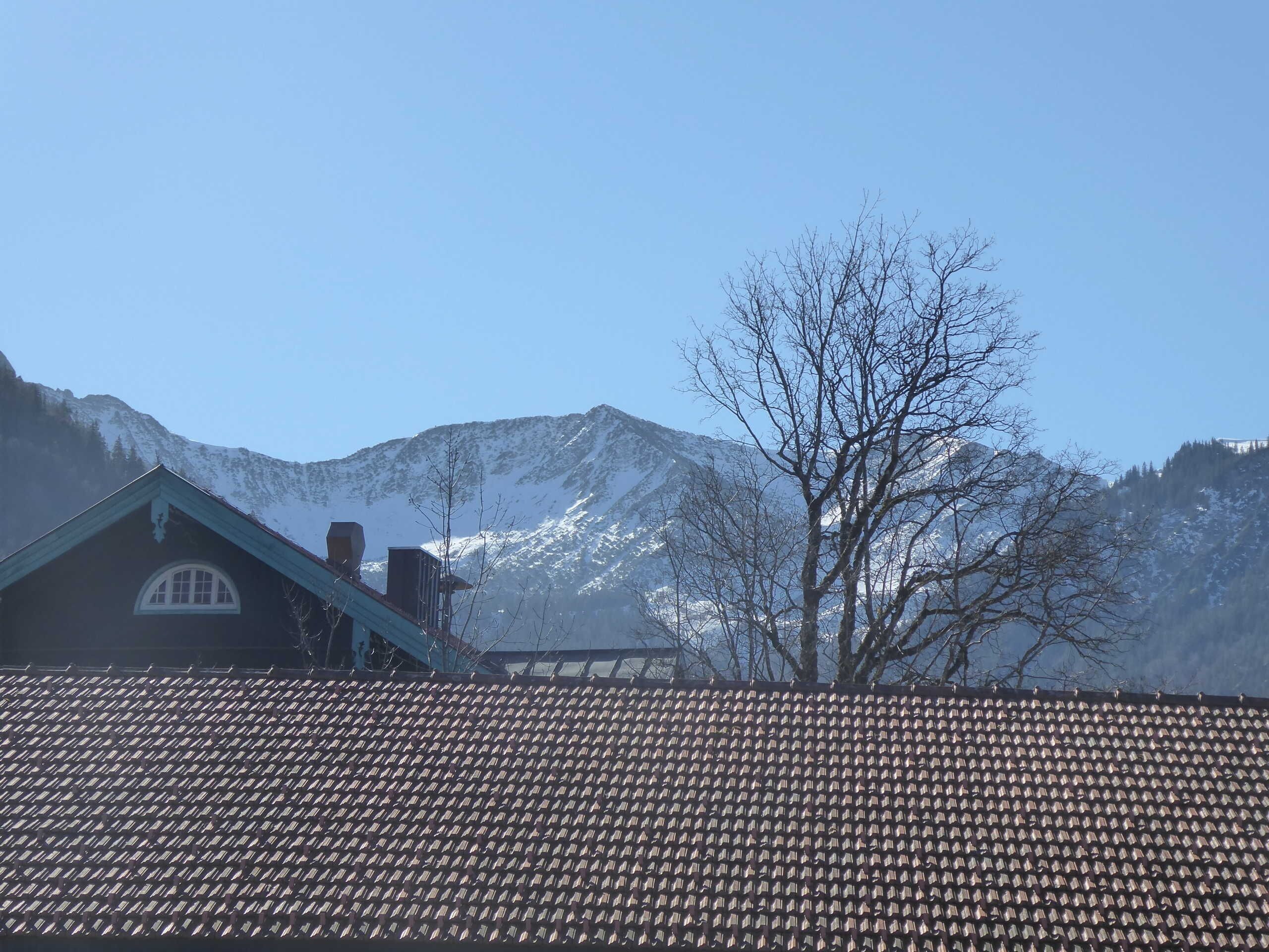 Eine Berglandschaft mit einem Gebäude, dessen Dach mit Ziegeln gedeckt ist, und einem wolkenlosen Himmel.