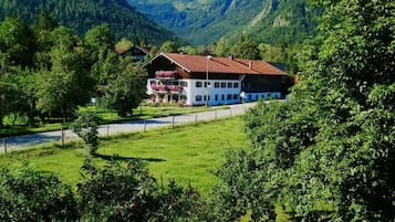 Ein Hotel mit rotem Dach, umgeben von üppiger Vegetation und Bergen.