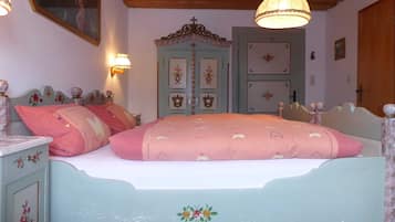 Ein Schlafzimmer mit einem Bett, einem Nachttisch, einer Kommode, einem Spiegel und einer Tür mit dekorativen Feld.