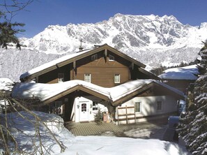 Situated in a mountainous area, this chalet-style building features a central entrance and two windows on each side.
