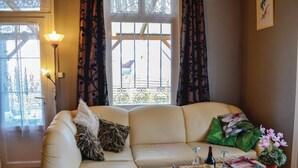 A cozy living room with a sofa, a small table with a wine bottle and glasses, and a potted plant. - 2 bedroom amazing home in Houlle (Houlle)