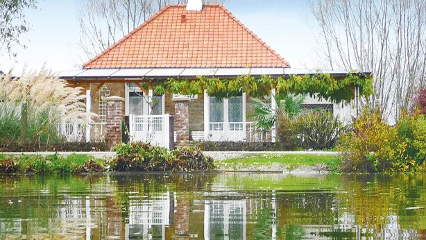 A house with a red-tiled roof, a brick facade, and a garden in front. - 2 bedroom amazing home in Houlle (Houlle)