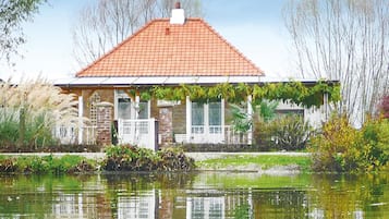 Een huis met een rood pannendak, een bakstenen gevel en een tuin ervoor.