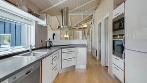 Una cocina moderna con gabinetes blancos, una campana de acero inoxidable y un horno empotrado.