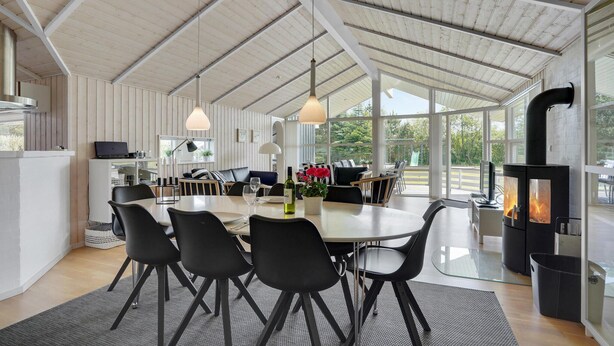Una cocina moderna con comedor, que incluye una mesa grande, sillas negras y una estufa empotrada.