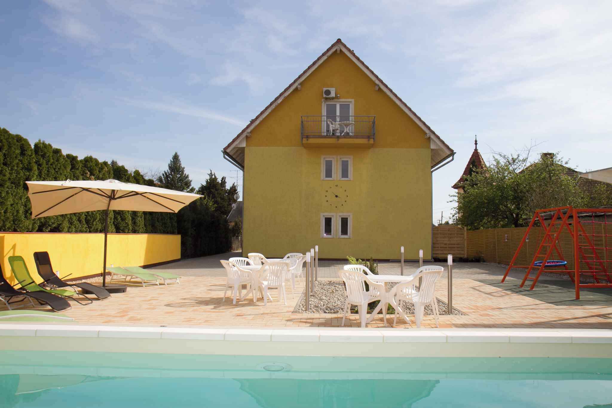 Un edificio amarillo con balcón, piscina y zona de estar al aire libre.