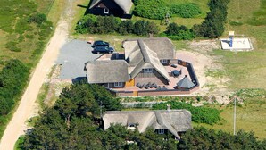 Vista aérea de uma casa com design arquitetônico singular, com vários telhados inclinados e um pátio central com área de estar ao ar livre.