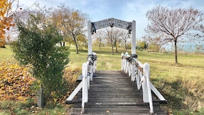 A wooden bridge with white railings and a sign above it.
