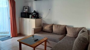 A living room with a sofa, a coffee table, a TV, and a kitchenette.
