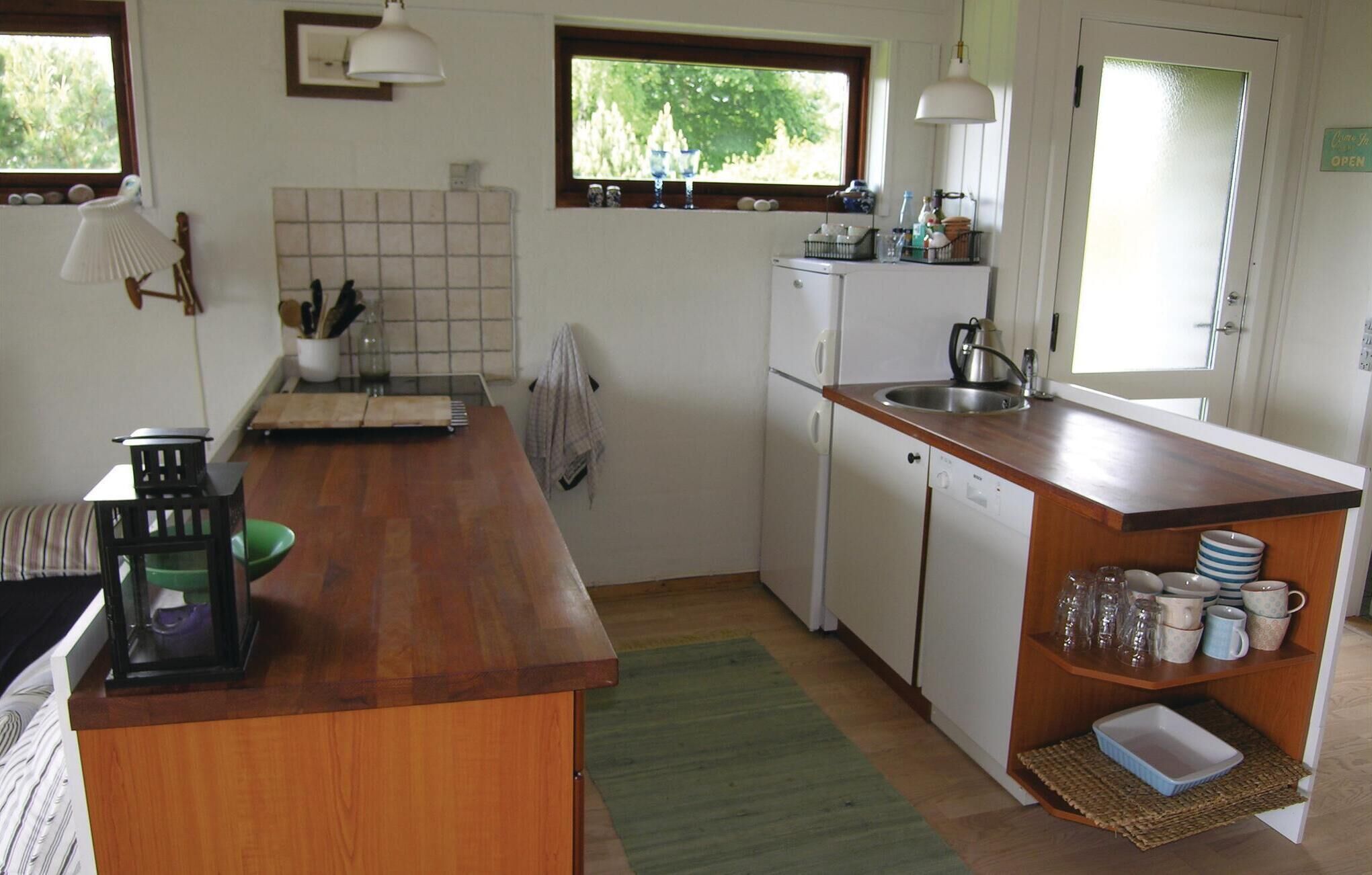 A compact kitchen with a wooden countertop, a built-in sink, and a refrigerator.