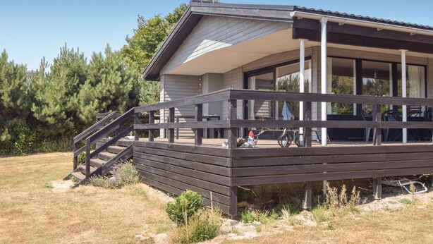 Ein modernes Haus mit einer Holzterrasse, einer überdachten Veranda und einer Treppe zum Eingang.