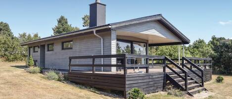 Une maison moderne de plain-pied, dotée d’un porche abrité et d’un escalier menant à l’entrée.