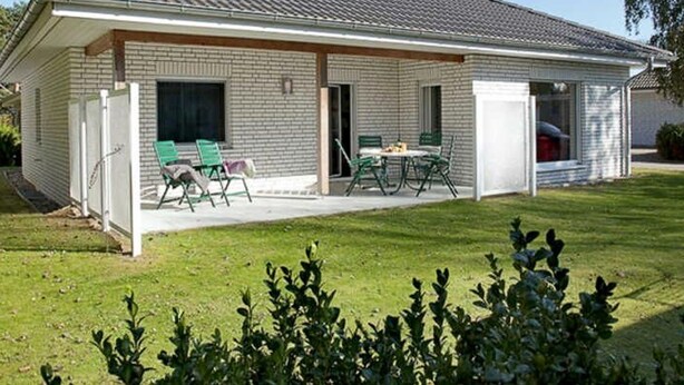 Einbungalow mit überdachter Terrasse, Garage und Rasen.