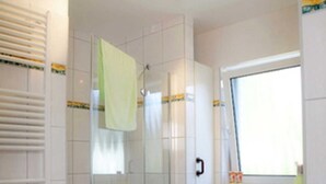Ein Badezimmer mit Waschmaschine, Duschkabine und Waschbecken.