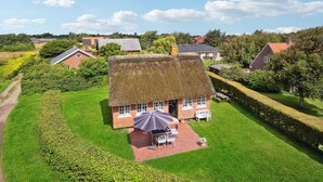 A thatched-roof house with a patio and a table with chairs. - 3 bedroom beautiful home in Fanø (Fanø)
