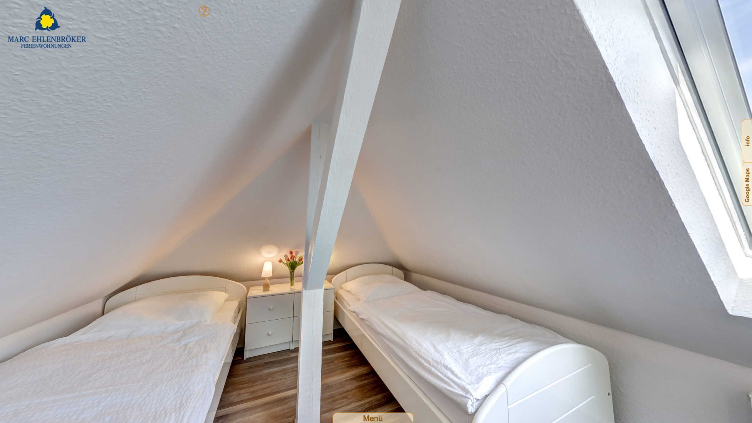 Une petite chambre blanche avec deux lits, un plafond en pente, une table de chevet avec une lampe et un vase rempli de fleurs.