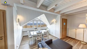 Una habitación acogedora con comedor, sofá y vista a la playa.