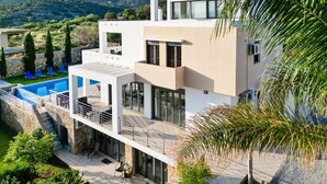 Ein modernes, zweistöckiges Haus mit Swimmingpool, Außenbereich zum Sitzen und Blick auf die Berge.