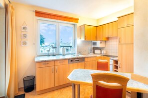 Una cucina compatta con mobili in legno, una finestra vista città, un forno a microonde e un lavello.