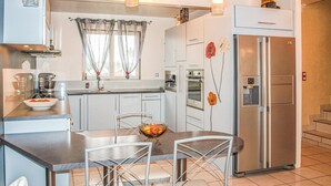 Una cocina moderna con electrodomésticos de acero inoxidable, un comedor con dos sillas y un refrigerador con dispensador de agua.