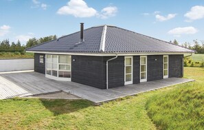 A modern house with a dark exterior, a sloped roof, and a wooden deck.
