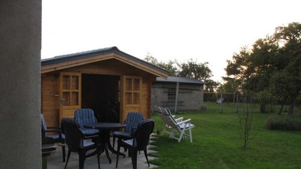 A wooden cabin with a patio area featuring two tables and four chairs.