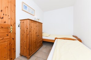Une chambre avec une armoire en bois, un lit et une petite table de chevet avec une lampe.