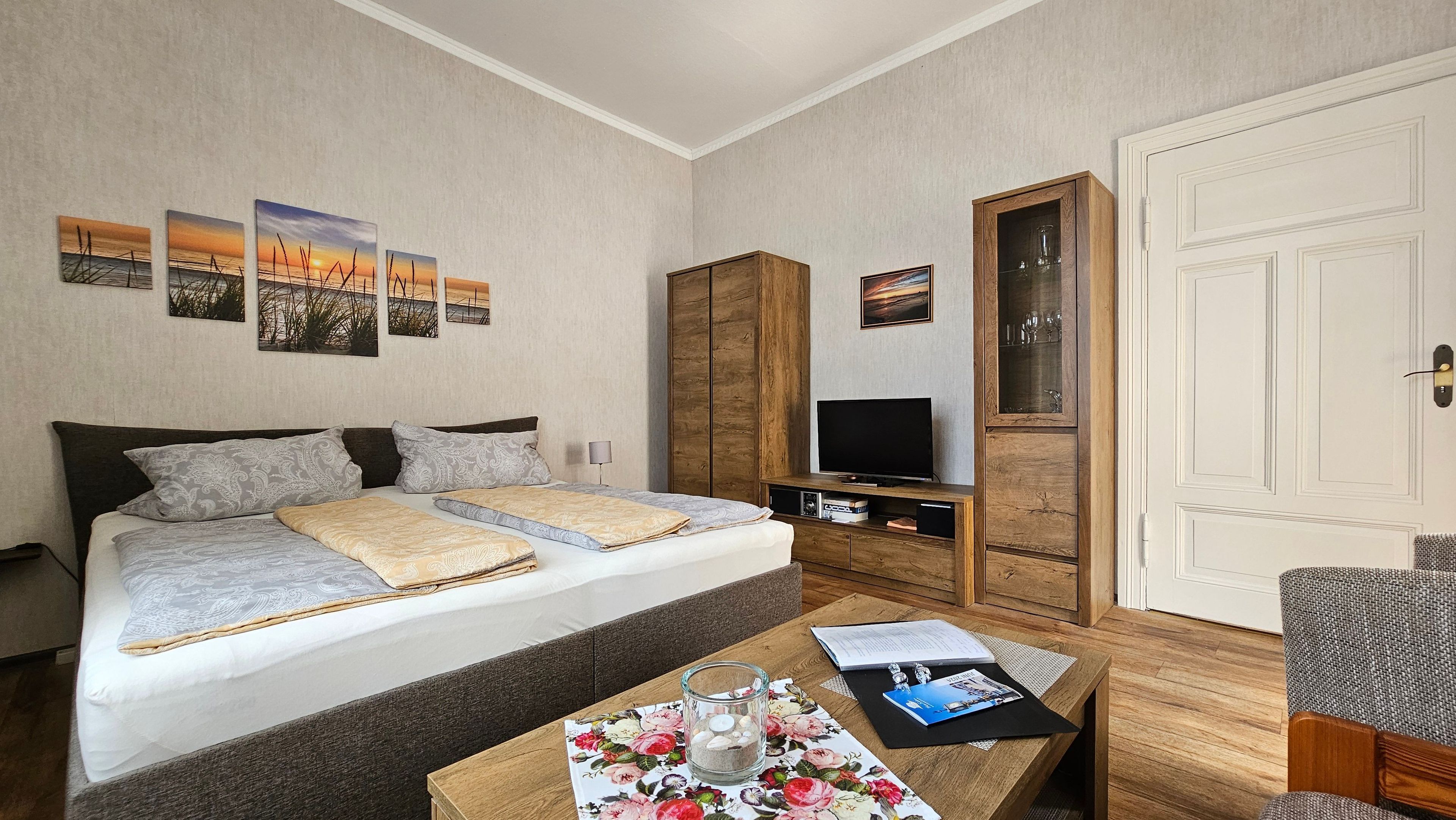 Hotelkamer met een bed, een televisie, een houten kledingkast, een bureau met een glas en een deur.