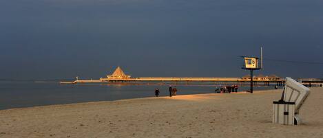 Een strand met een steiger, een redershut en een stoel.