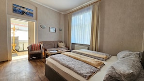 A hotel room with two beds, a sofa, a chair, a table, and a view of the sea through the window. - Vacation apartment - Bungalow & vacation apartment Fuchs (Heringsdorf)