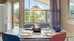 A dining area with a table set for four, large windows, and a view of greenery outside. - Gorgeous home in Fjerritslev with sauna (Fjerritslev)