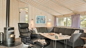 A cozy living room with a black leather sofa, a white table, and a wood-burning stove. - Gorgeous home in Fjerritslev with sauna (Fjerritslev)