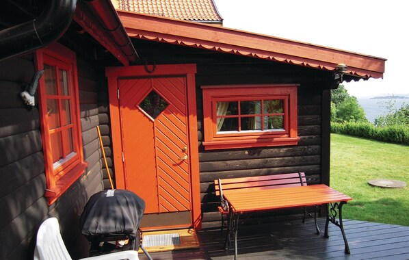 A wooden cabin with a red door and window, a bench, and a small table on a deck. - Stunning home in åsgårdstrand with WiFi (Åsgårdstrand)