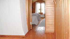 Un estrecho pasillo de madera que conduce a un dormitorio con una cama y una ventana.